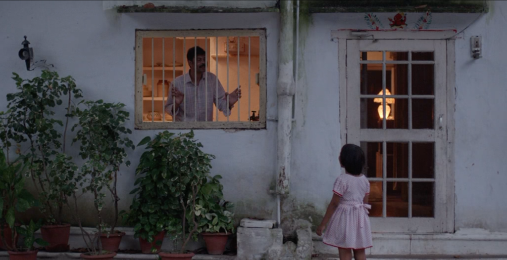 Zdjęcie przedstawiające mężczyznę wyglądającego przez okno i dziewczynkę, która mu się przygląda.