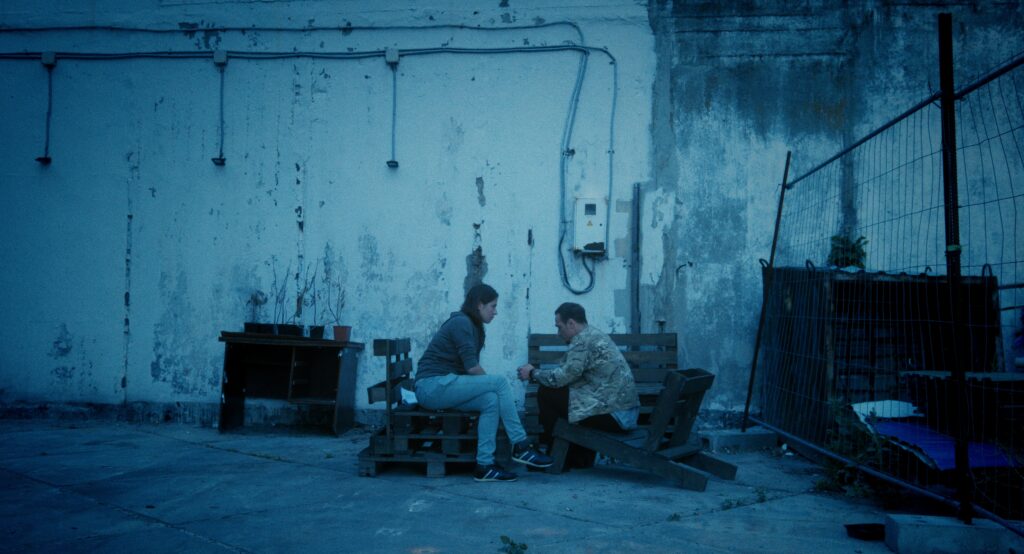 Zdjęcie przedstawiające młodych kobietę i mężczyznę siedzących na paletach.