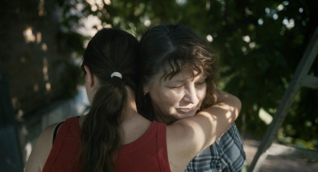 Zdjęcie przedstawiające młodą kobietę przytulającą kobietę w średnim wieku.