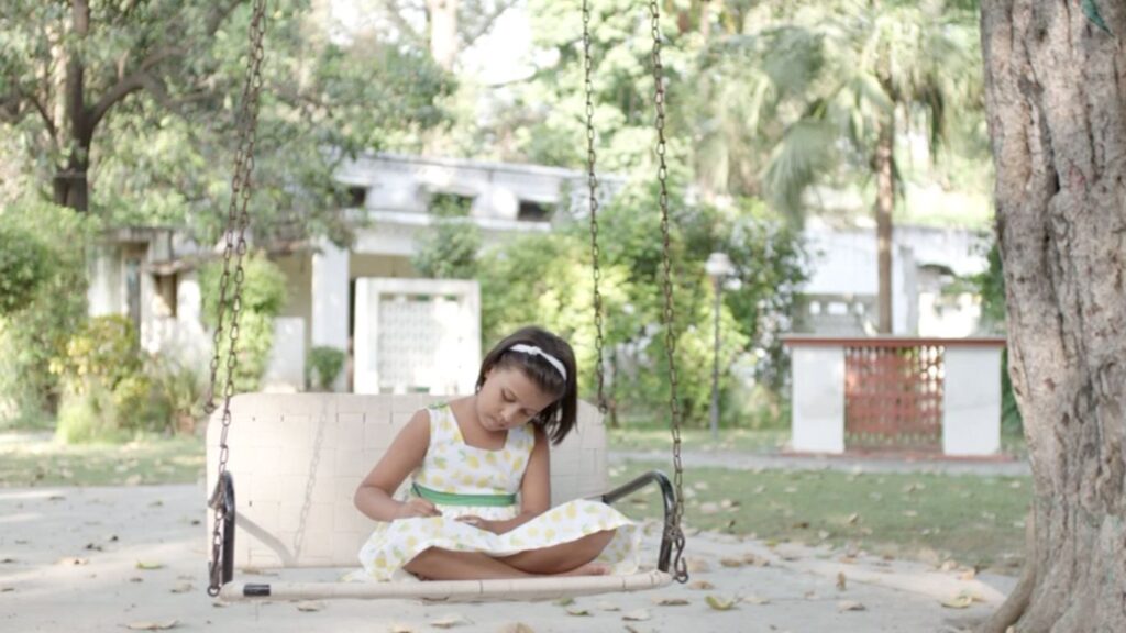 WRÓŻKI SHANKARA. Zdjęcie przedstawiające dziewczynkę siedzącą na huśtawce.